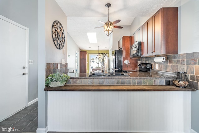 kitchen with sink, tasteful backsplash, a textured ceiling, dark tile patterned floors, and black appliances