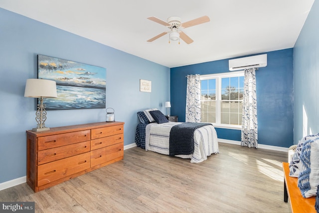 bedroom with ceiling fan, a wall mounted AC, and light wood-type flooring