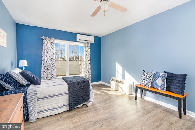 bedroom with ceiling fan, light wood-type flooring, and a wall unit AC