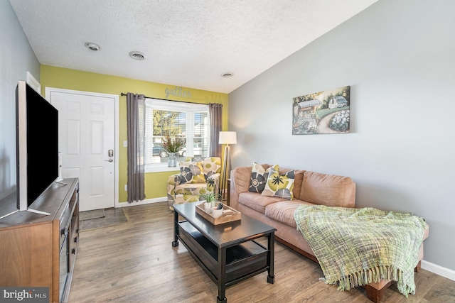 living room with hardwood / wood-style flooring, lofted ceiling, and a textured ceiling