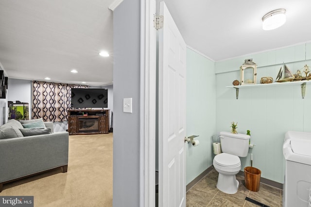 bathroom featuring toilet, ornamental molding, and washer / clothes dryer