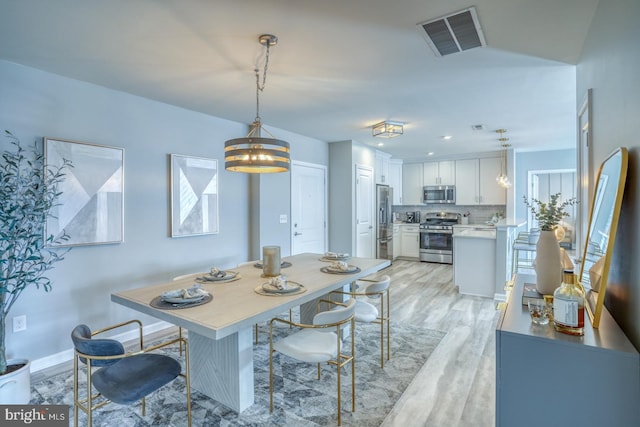 dining space with a chandelier and light wood-type flooring