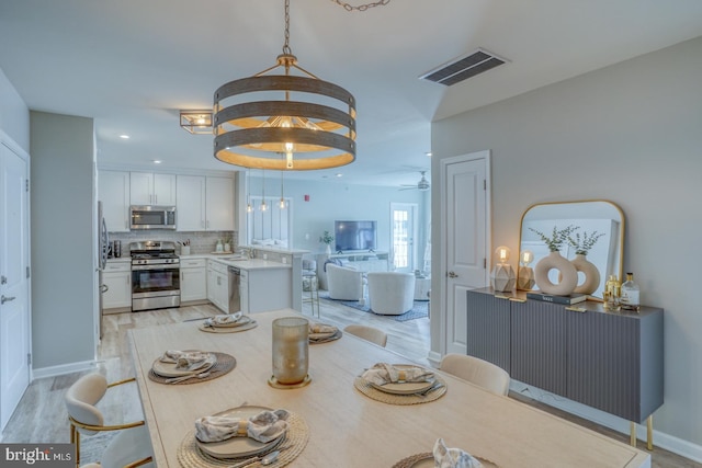 dining room featuring ceiling fan, sink, and light hardwood / wood-style floors