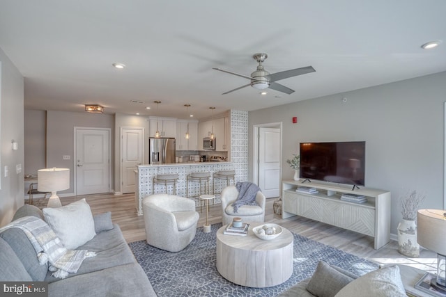 living room with ceiling fan and light hardwood / wood-style floors