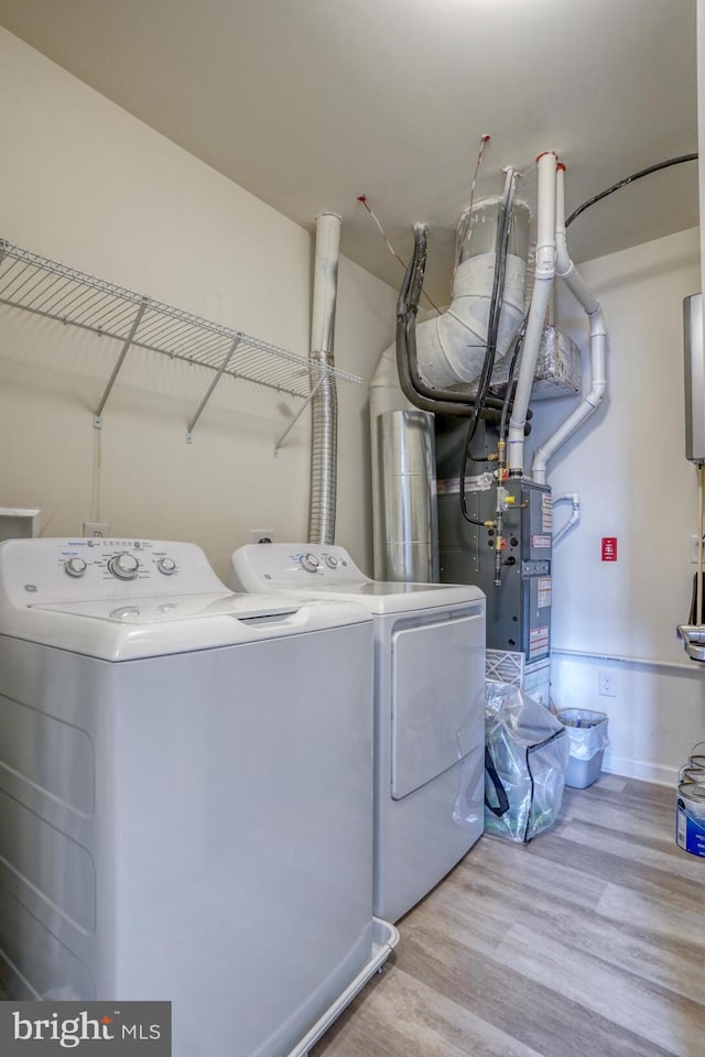 clothes washing area with separate washer and dryer and light hardwood / wood-style flooring