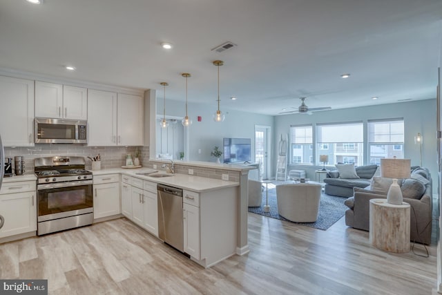 kitchen with white cabinetry, hanging light fixtures, kitchen peninsula, and appliances with stainless steel finishes