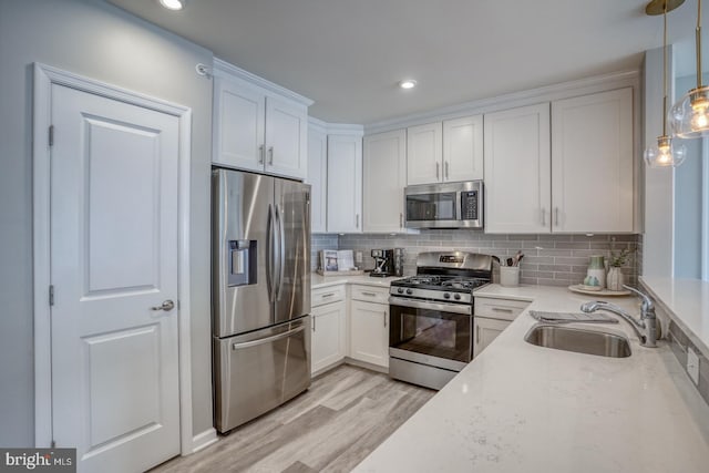 kitchen featuring sink, stainless steel appliances, decorative backsplash, white cabinets, and decorative light fixtures