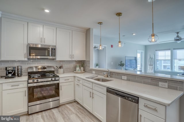 kitchen with pendant lighting, stainless steel appliances, sink, and white cabinets