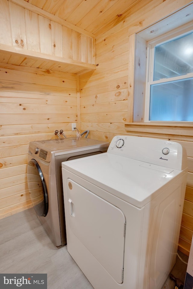 clothes washing area featuring separate washer and dryer, wood ceiling, and wooden walls