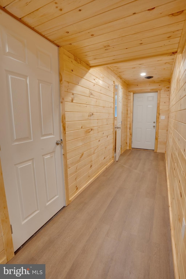 hall featuring wooden walls, wooden ceiling, and light hardwood / wood-style floors