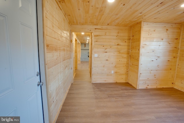 empty room featuring light hardwood / wood-style flooring, wood ceiling, and wooden walls