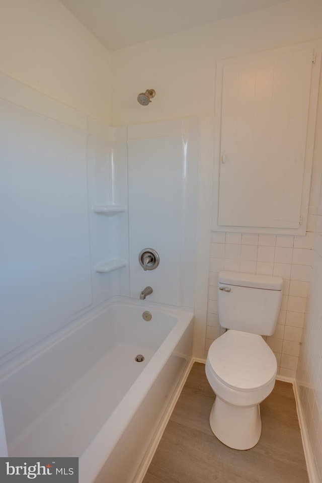 bathroom with wood-type flooring, bathing tub / shower combination, and toilet