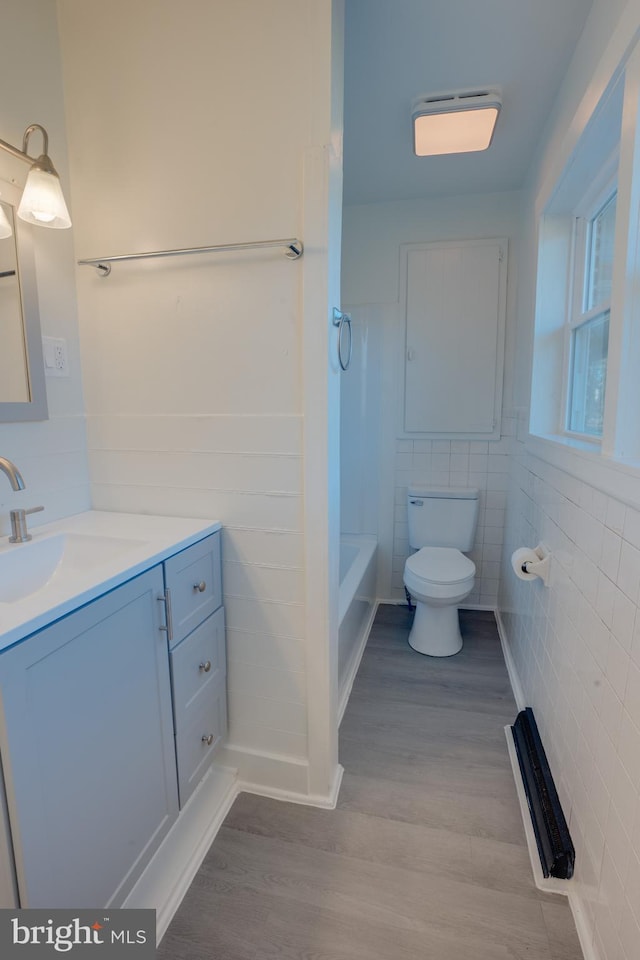 bathroom with vanity, toilet, hardwood / wood-style floors, and tile walls