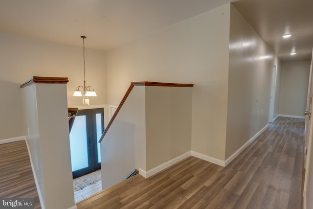 corridor featuring dark hardwood / wood-style floors, a notable chandelier, and french doors