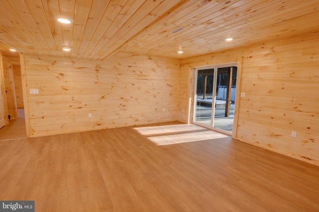 empty room featuring wood ceiling, wooden walls, and light hardwood / wood-style floors