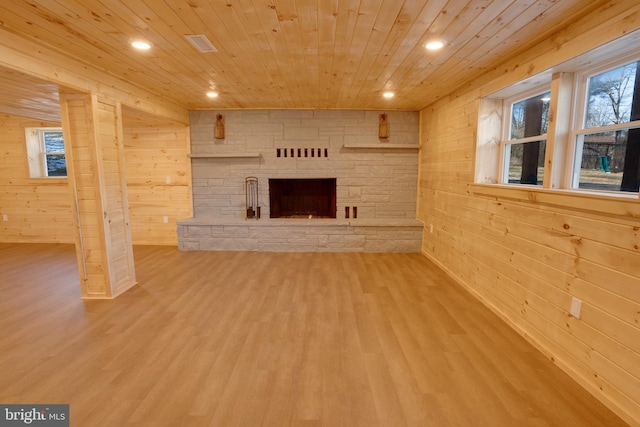 unfurnished living room featuring wood ceiling, a fireplace, hardwood / wood-style flooring, and wood walls