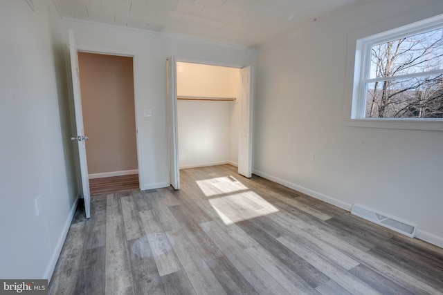 unfurnished bedroom with ornamental molding, a closet, and light wood-type flooring