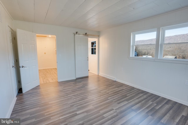 unfurnished bedroom featuring a barn door and hardwood / wood-style floors