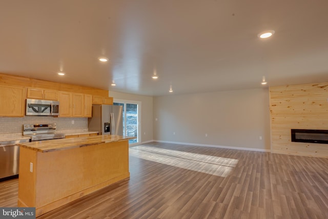 kitchen with a kitchen island, decorative backsplash, stainless steel appliances, light brown cabinets, and light hardwood / wood-style flooring