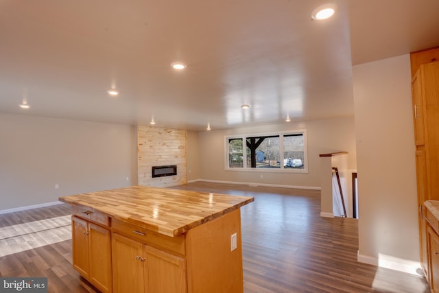 kitchen featuring a kitchen island, dark hardwood / wood-style floors, a fireplace, wood counters, and light brown cabinets