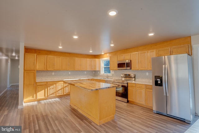 kitchen featuring a kitchen island, appliances with stainless steel finishes, light brown cabinetry, and light hardwood / wood-style flooring