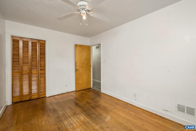 unfurnished bedroom with ceiling fan, dark wood-type flooring, a textured ceiling, and a closet