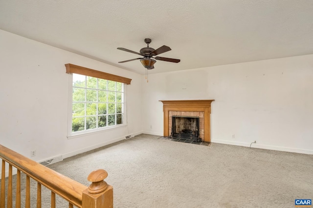 unfurnished living room featuring ceiling fan, carpet flooring, a textured ceiling, and a fireplace