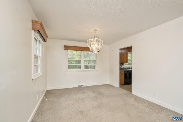 unfurnished room featuring light carpet, a textured ceiling, and an inviting chandelier