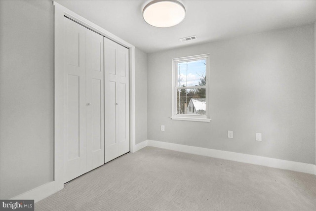 unfurnished bedroom featuring light carpet and a closet