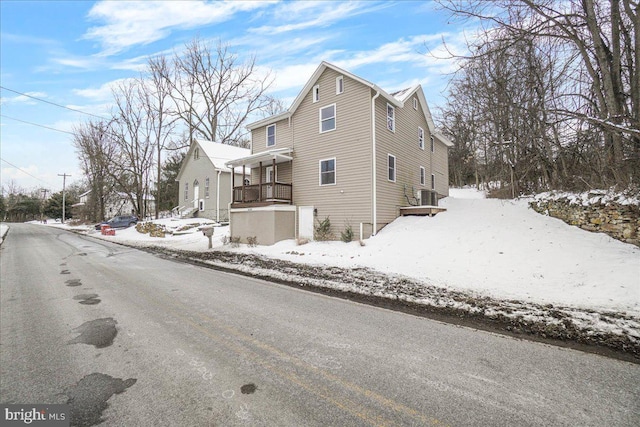 snow covered property with covered porch and central air condition unit