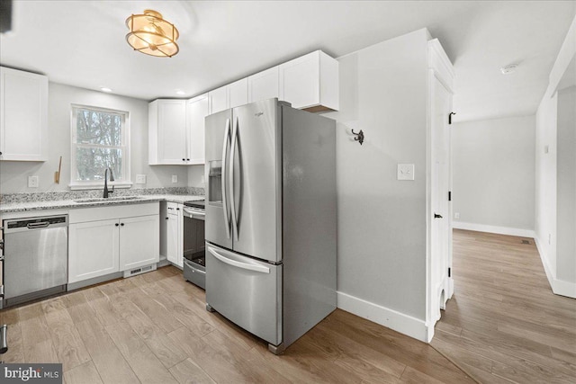 kitchen with appliances with stainless steel finishes, sink, and white cabinets