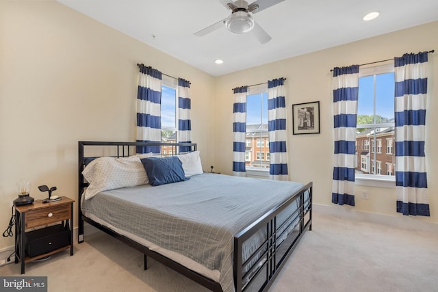 carpeted bedroom featuring multiple windows and ceiling fan