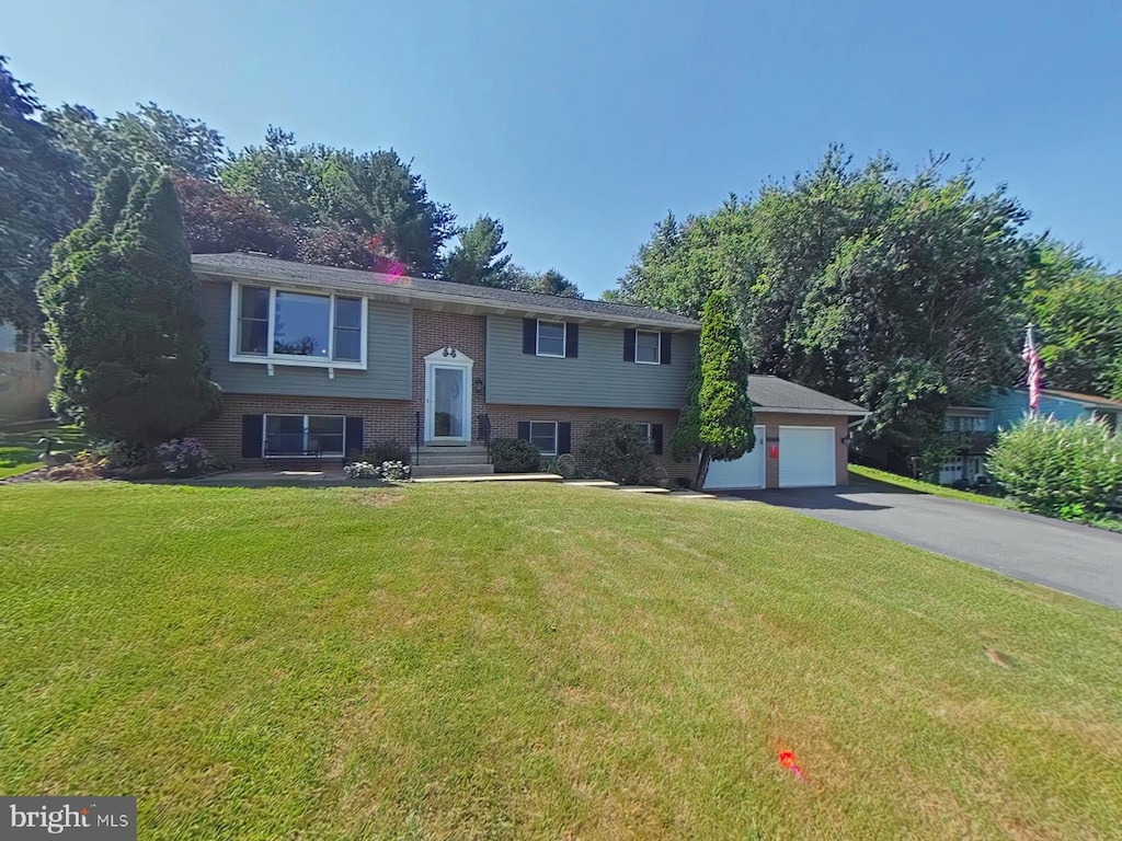 raised ranch with an outbuilding, a garage, and a front yard