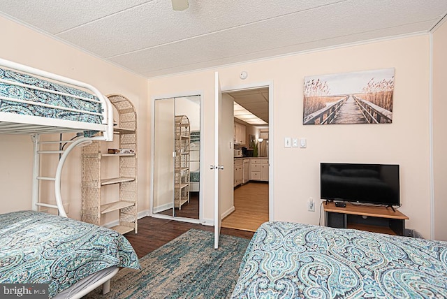 bedroom featuring a textured ceiling, ornamental molding, dark hardwood / wood-style flooring, a closet, and ceiling fan