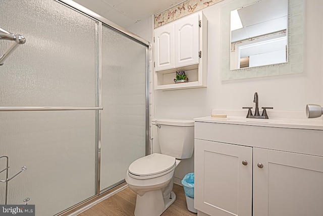 bathroom featuring wood-type flooring, toilet, vanity, and a shower with shower door