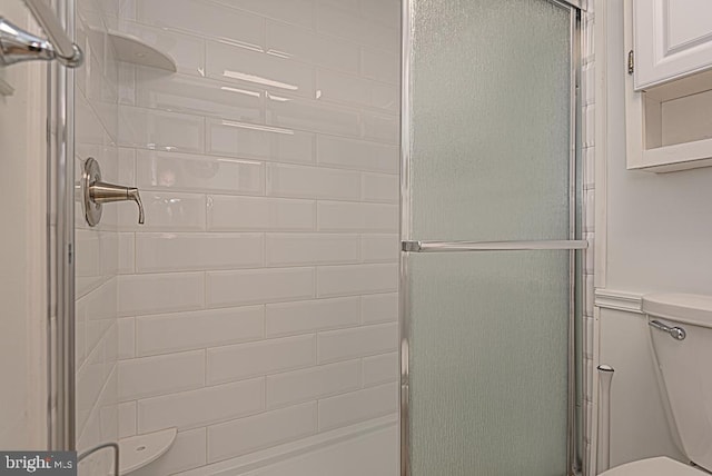 bathroom featuring toilet and a shower with door