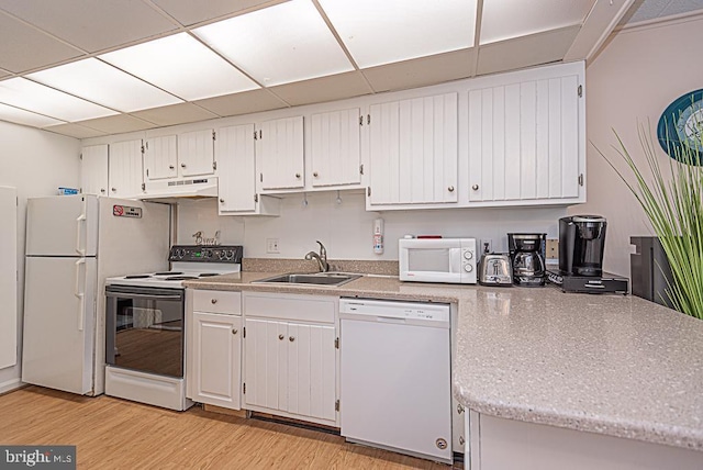 kitchen featuring sink, white appliances, light hardwood / wood-style flooring, white cabinetry, and a drop ceiling