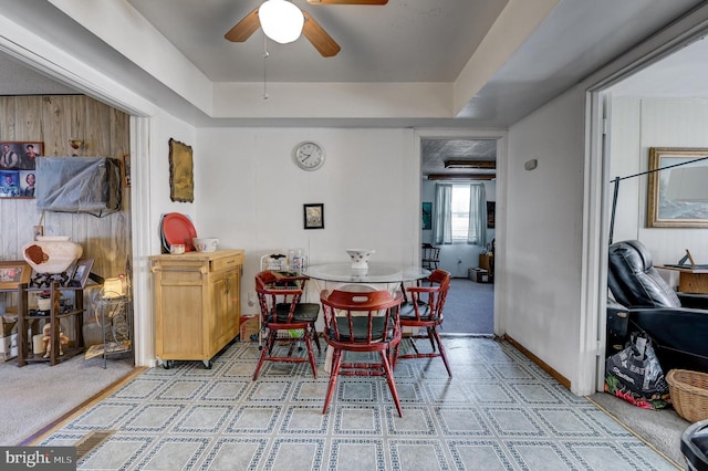 carpeted dining room with ceiling fan and wood walls