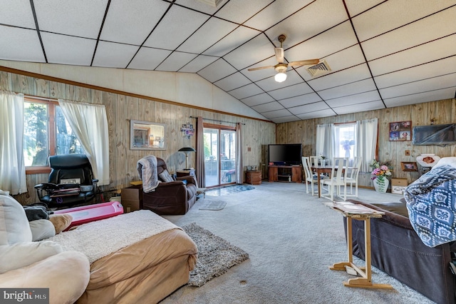 living room featuring lofted ceiling, wooden walls, ceiling fan, carpet, and a drop ceiling