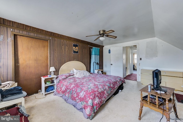 carpeted bedroom with ceiling fan and wood walls