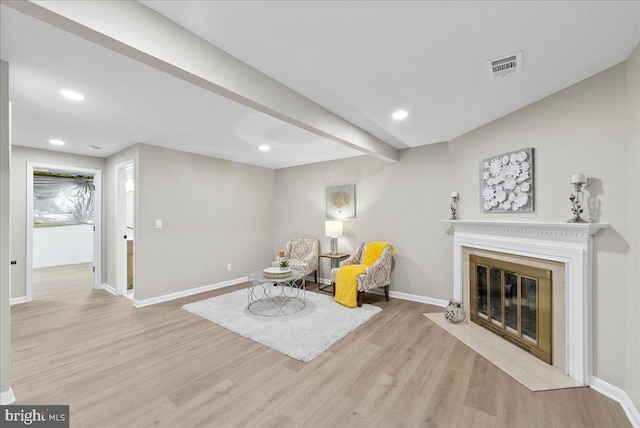 living area with light hardwood / wood-style floors and beamed ceiling