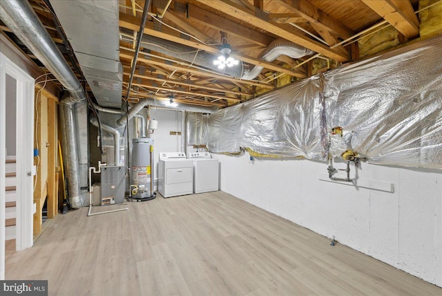 basement with washer and dryer, heating unit, water heater, and light wood-type flooring