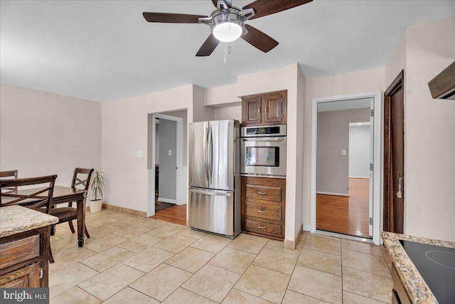 kitchen with light stone counters, ceiling fan, stainless steel appliances, and light tile patterned floors