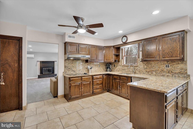 kitchen featuring sink, ceiling fan, black electric stovetop, light stone countertops, and backsplash