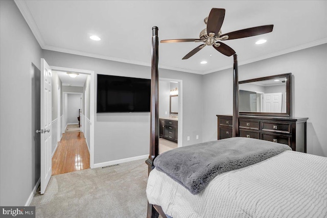 bedroom featuring crown molding, light colored carpet, ensuite bathroom, and ceiling fan