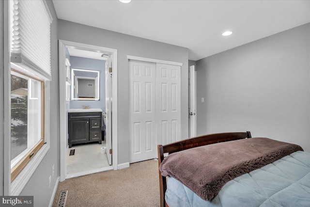 bedroom with ensuite bath, carpet flooring, sink, and a closet