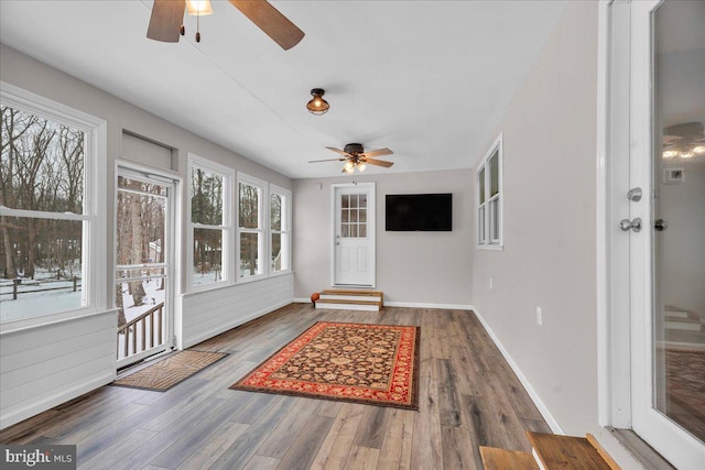 unfurnished sunroom featuring ceiling fan