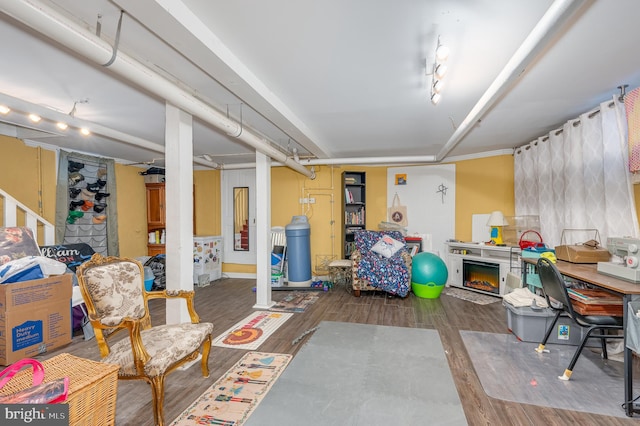 basement with rail lighting and dark hardwood / wood-style flooring