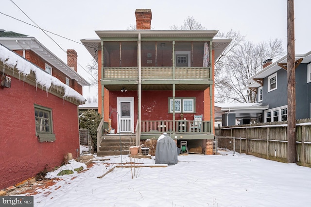 snow covered rear of property with a balcony