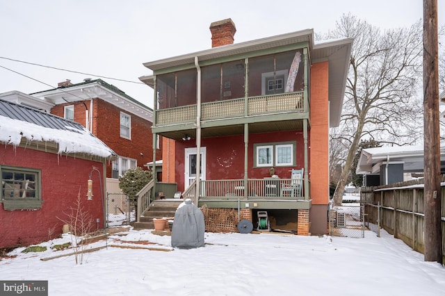 snow covered back of property featuring a balcony